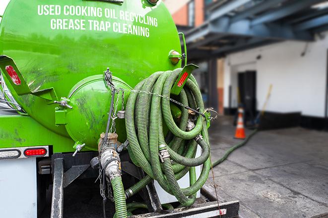 a professional plumber using a pump to empty a grease trap in Bell Canyon